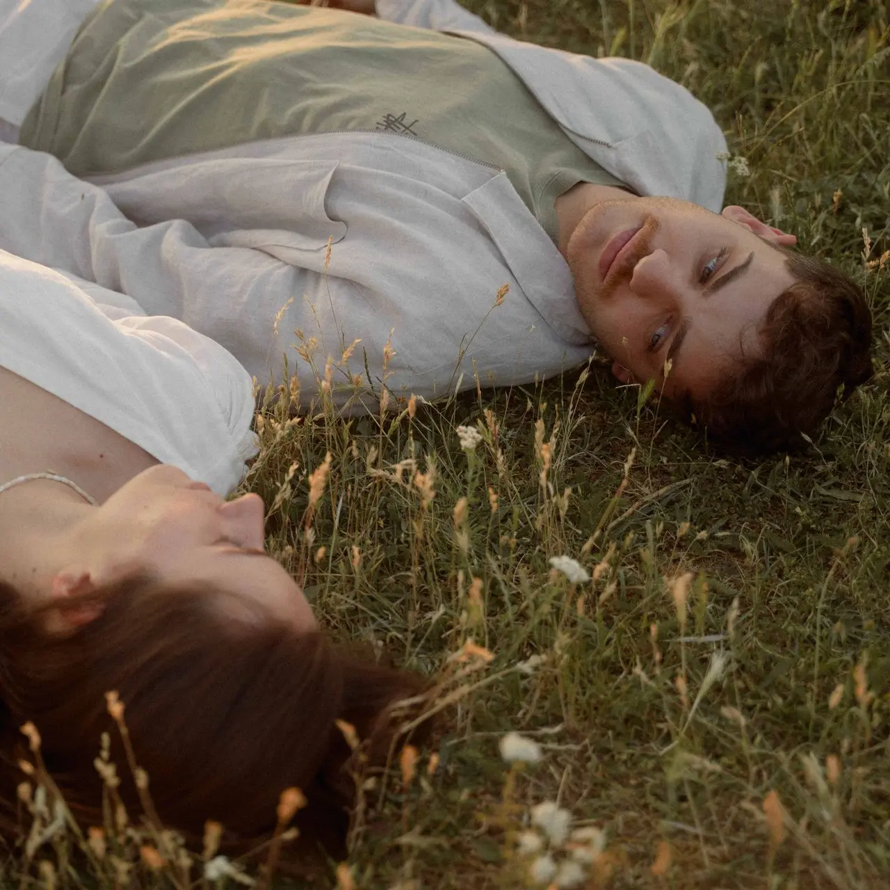Photograph from Elopement Photographer Switzerland Nat Russer showing an image inspired from Twilight and Pride and Prejudice, showing a of a couple laying on the grass and looking at each other in the Swiss Alps.