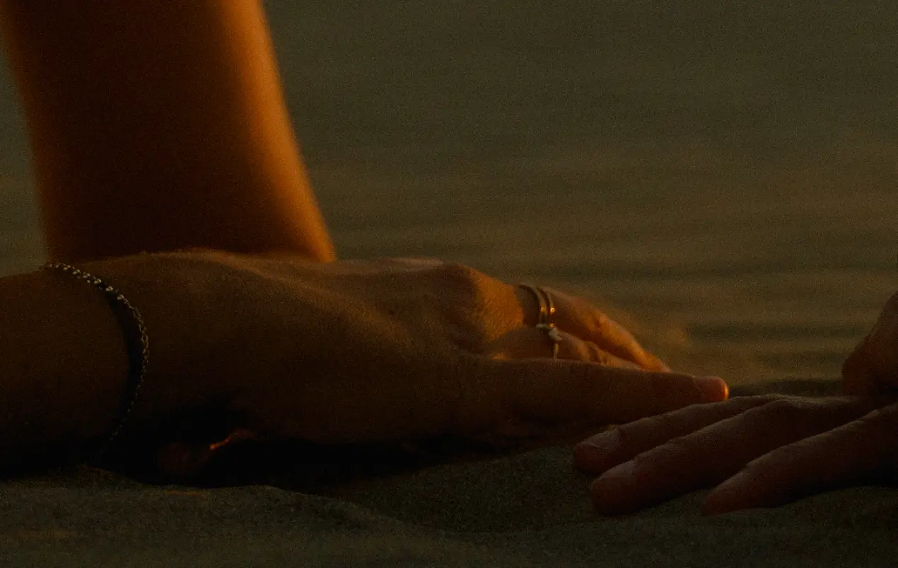 Soulful and romantic photograph of two hand gently touching each other at sunset.
