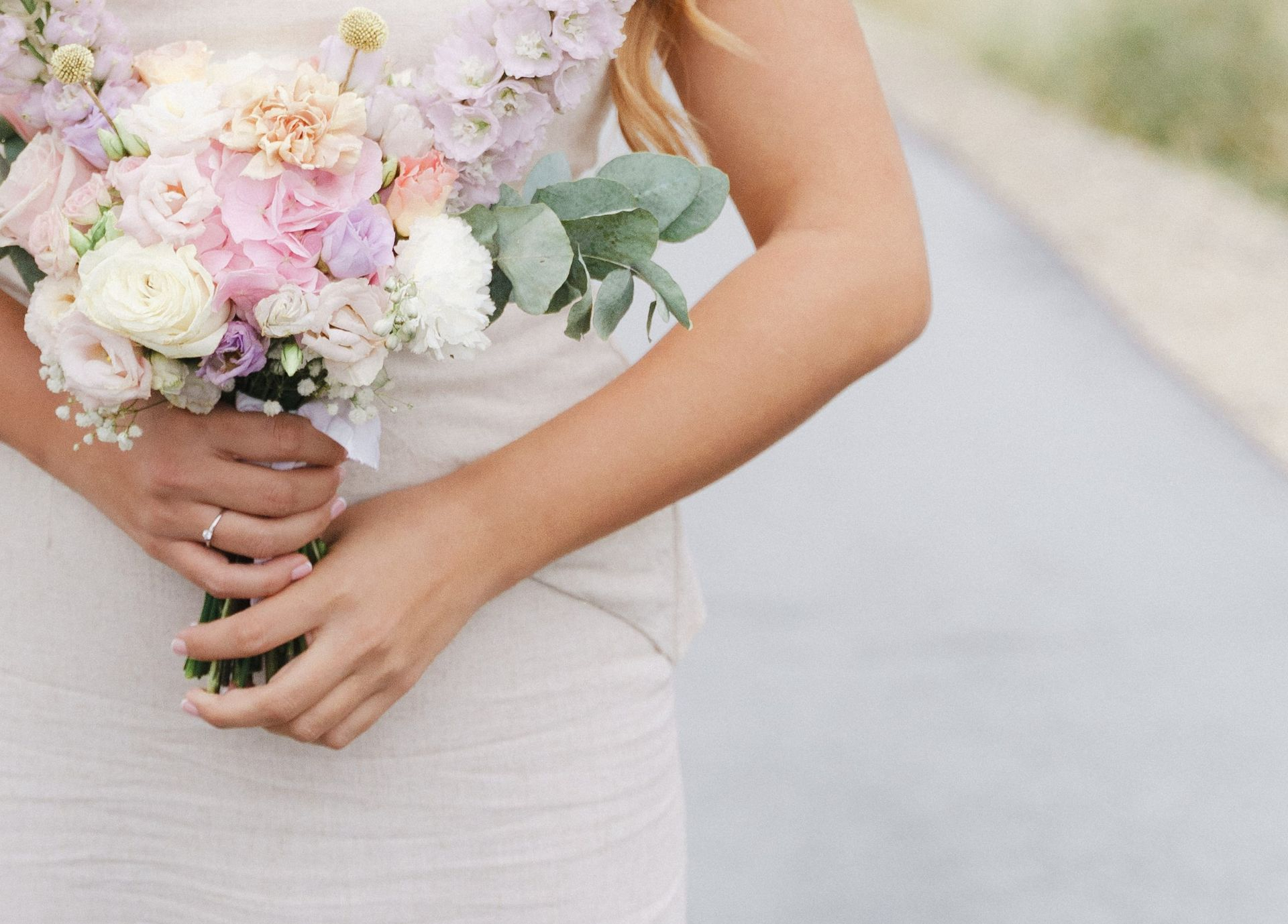 A woman holding a pasel-coloured wedding bouquet