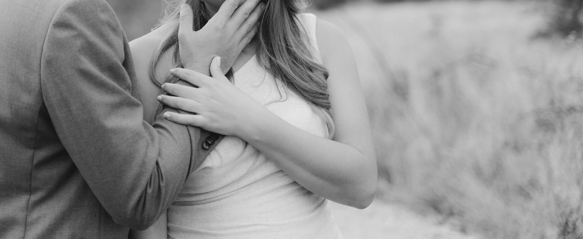 black and white image of two people hugging in gentle embrace. no faces shown.